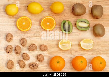 Draufsicht auf verschiedene Früchte, Zitronen, Orangen, Kiwi-Früchte und Nüsse, ganze und geschnittene Früchte Stockfoto