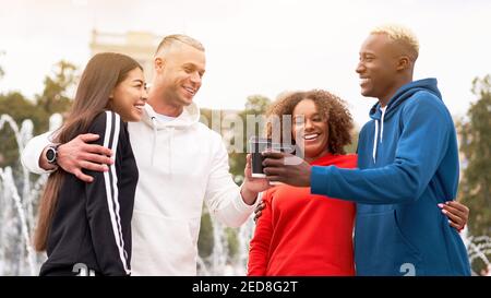 Multiethnische Gruppe Teenager Freunde. afroamerikanisch asiatisch kaukasisch Student verbringen Zeit zusammen multirassische Freundschaft glücklich lächelnde Menschen gekleidet bunte Sportbekleidung trinken Kaffee im Freien Stockfoto