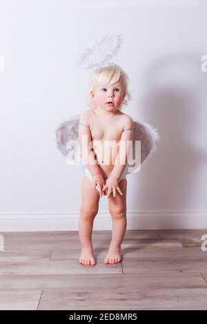 Das Baby mit Engelsflügeln und Nimbus drinnen Stockfoto