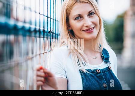 Porträt einer blonden Frau mit blauäugigen Augen in Jeans mit Hosenträgern Stockfoto