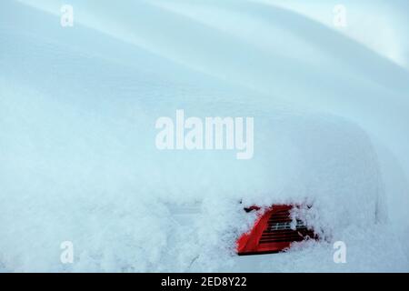 Schneebedecktes weißes Auto und seine rote Rückleuchte. Schottischer Winterhintergrund Stockfoto