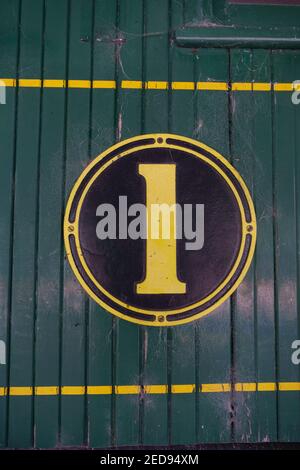 Altweltnummer 1 in gelbem Kreis auf dunkelgrünem Holzhintergrund. Stockfoto