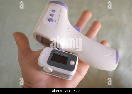 Mann halten Pulsoximeter und digitales Fieberthermometer, Sauerstoffsättigung in covid19 pandemische Krankheit, medizinische Heimüberwachung Behandlung Stockfoto