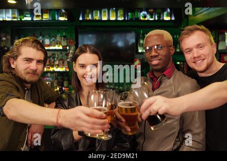 Gruppe von glücklichen jungen Fußball-Fans klirren mit Gläsern Bier vor der Kamera, während sie den Sieg ihrer feiern Lieblingsfußballmannschaft Stockfoto