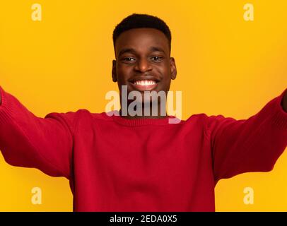 Selfie-Zeit. Fröhlicher junger afroamerikanischer Kerl, der Selbstporträt macht und lächelt Stockfoto