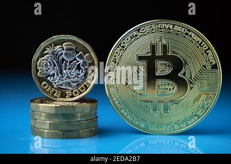 Bitcoin und britische 1-Pfund-Münzen zusammen auf der reflektierenden Oberfläche mit verschwommenem Hintergrund platziert. Konzept für Kryptowährung im Vergleich zu herkömmlicher Curre Stockfoto
