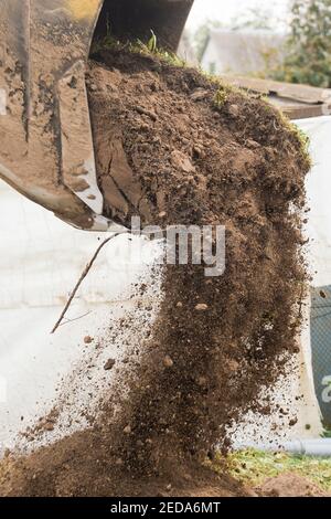 Ein Bulldozer gießt einen Eimer Land auf einer Baustelle aus der Nähe. Aushubarbeiten in der Industrie. Stockfoto