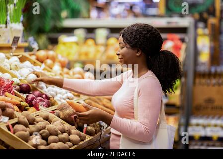 Seitenansicht einer schönen schwarzen Dame, die Gemüse kauft Großer Supermarkt Stockfoto