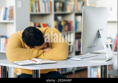 Müde männliche Angestellte oder Student schlafen am Schreibtisch im Büro ein. Erschöpfter Freiberufler arbeitete online Überarbeit, brauchen eine Pause Stockfoto