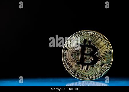 Bitcoin auf der reflektierenden Oberfläche mit verschwommenem Hintergrund platziert. Konzept für Kryptowährung. Großer Kopierspeicher. Stockfoto