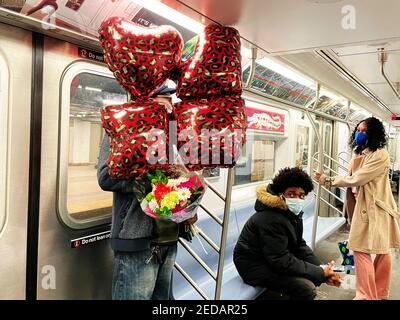 New York City, New York, USA. Februar 2021, 13th. Ab ValentineÃ¢â‚¬â„¢s Day, New York City Restaurants wurden erlaubt, ihre Indoor-Dining-Abschnitte mit 25% Kapazität nach einem zweimonatigen Verbot von Gov instandgesetzt wieder zu öffnen. Andrew Cuomo letzten Dezember. Eine Entscheidung, die die New Yorker dazu brachte, das Ereignis erneut auf eine beispiellose Art und Weise zu feiern, obwohl viele Geschäfte geschlossen bleiben. Dieses Paar stieg in den Zug ein, der Herr hatte seine Arme voller Blumen und roter Ballons Credit: Marie Le BLE/ZUMA Wire/Alamy Live News Stockfoto