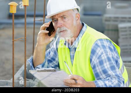 Leitender Ingenieur, der bei der Arbeit ein Smartphone verwendet Stockfoto