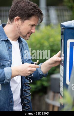 Junger Mann, der für den Parkplatz am Automaten bezahlt Stockfoto