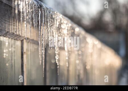 Scharfe Eiszapfen auf dem Dach des Gewächshauses im sonnigen Winter Tag auf der Sonnenseite Stockfoto