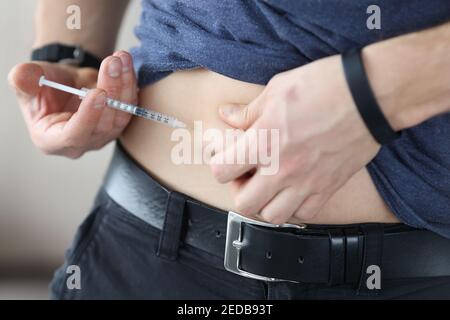 Der Mensch injiziert sich mit einer Insulinspritze in den Magen Stockfoto