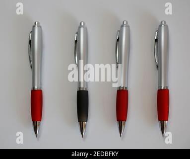 Drei rote Kugelschreiber und ein schwarzer ein Odd-One-Out Stockfoto