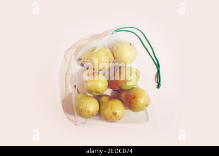 Wiederverwendbare Verpackung von Produkten nach Gewicht. Birnen in einem wiederverwendbaren Beutel Nahaufnahme auf einem rosa Hintergrund Stockfoto