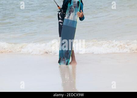 Ein Sportler hält vertikal ein Kite-Boarding-Board am Meer. Im Hintergrund das mexikanische Karibische Meer. Stockfoto