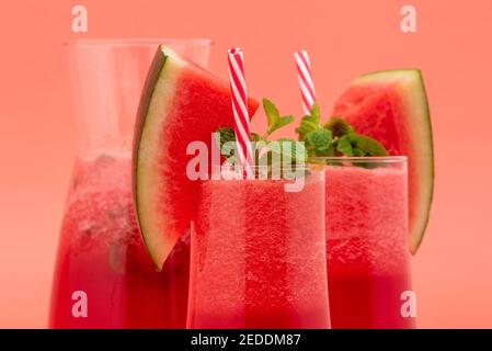 Erfrischende kalte Wassermelone Fruchtsaft Smoothies Getränke in den Gläsern Auf korallenrosa Hintergrund Stockfoto