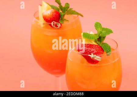 Nahaufnahme von farbenfrohen erfrischenden Erdbeer-Orange-Cocktail-Drinks bei Sonnenaufgang In den Gläsern auf korallenrosa Hintergrund Stockfoto