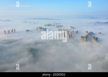 Peking, China. Februar 2021, 14th. Das am 14. Februar 2021 aufgenommene Foto zeigt Wolkenkratzer, die im Nebel gehüllt sind, im Guanshanhu-Bezirk von Guiyang, der Hauptstadt der südwestlichen Provinz Guizhou. Quelle: Liu Xu/Xinhua/Alamy Live News Stockfoto