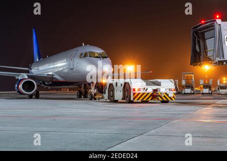 Schlepper schiebt Passagierflugzeuge von der Bordbrücke in der Nacht flughafenschürze Stockfoto