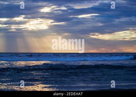 Sonnenstrahlen, die durch die Wolken über dem Pazifischen Ozean scheinen, aufgenommen vom Santa Teresa Strand, Costa Rica. Stockfoto