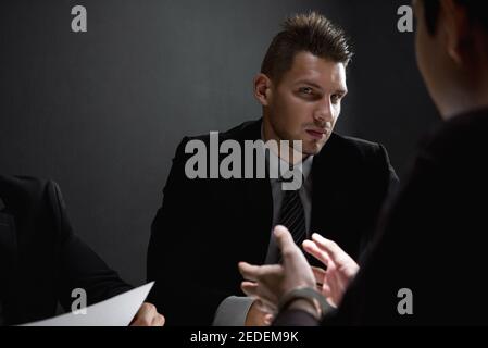 Detektive interviewen Verdächtigen oder kriminellen Mann in dunklen Verhörraum Stockfoto