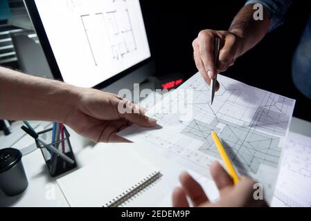 Architekten- oder Ingenieurteam, das das Projekt auf einem Blueprint in diskutiert Dunkles Büro spät in der Nacht Stockfoto