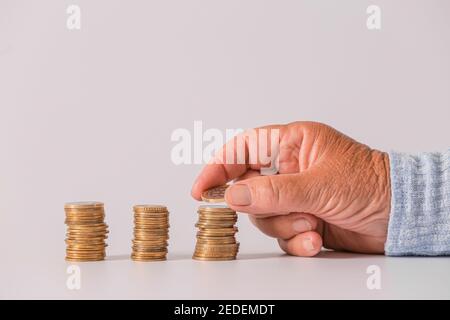 Hand der älteren Frau mit Münzen auf hellem Hintergrund. Konzept der Rente Stockfoto