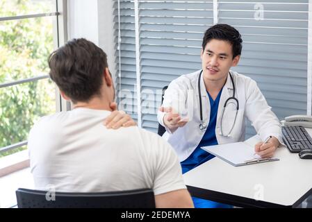 Männlicher Athlet Patient Beratung mit Arzt über Hals und Rücken Schmerzen in der Klinik Stockfoto