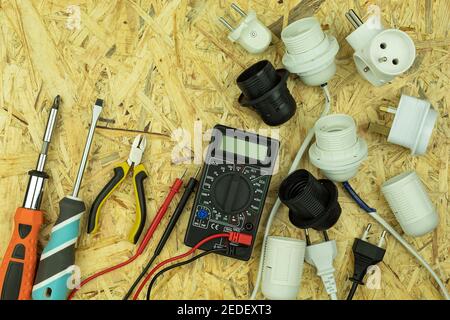 Installation der elektrischen Verdrahtung und Anschluss von Steckdosen und Steckern an Drähte. Elektrische Gegenstände und Werkzeuge werden mit leeren sp. Auf dem Tisch verteilt Stockfoto