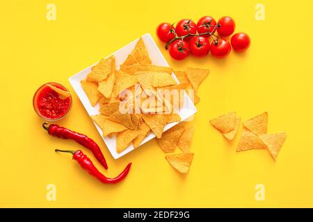 Platte mit leckeren Nachos und Sauce auf Farbhintergrund Stockfoto