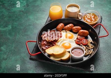 Traditionelles englisches Frühstück mit Spiegeleiern in der Pfanne auf Farbe Hintergrund Stockfoto