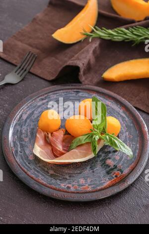 Teller mit köstlicher Melone und Prosciutto auf dunklem Hintergrund Stockfoto