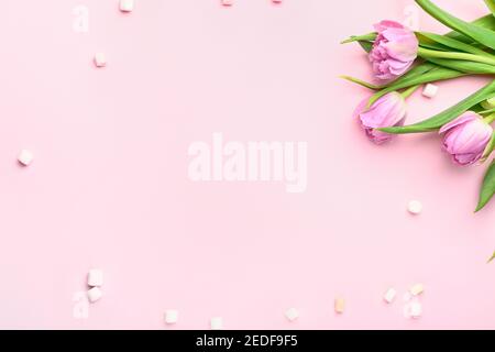 Schöne Tulpenblüten mit Marshmallows auf farbigem Hintergrund Stockfoto