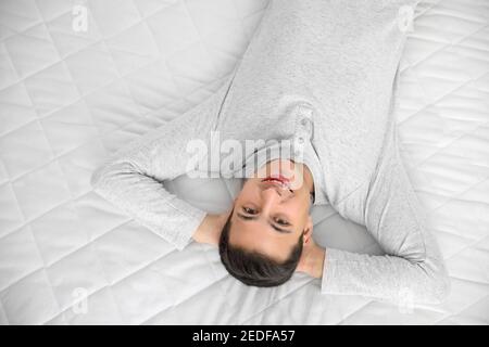 Morgen des jungen Mannes, der auf weicher Matratze lag, Blick von oben Stockfoto