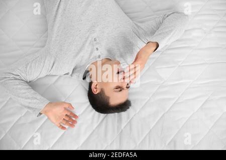 Morgen des jungen Mannes, der auf weicher Matratze lag, Blick von oben Stockfoto