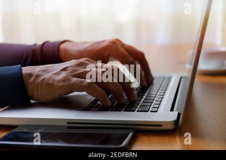 Nahaufnahme Geschäftsmann mit Laptop-Computer zu Hause. Nahaufnahme männliche Hände tippen auf Laptop-Tastatur im Büro. Mann Hände mit Laptop-Tastatur. Nahaufnahme Stockfoto
