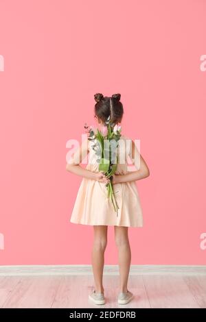 Nettes kleines Mädchen mit Blumenstrauß in der Nähe von Farbe Wand Stockfoto