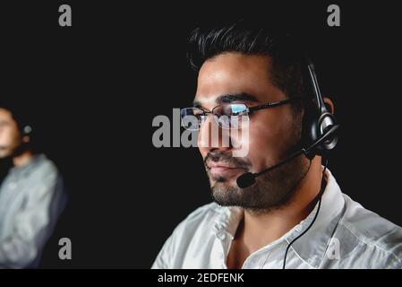 Männliche asiatische Kundenbetreuungsunternehmen, die in der Nachtschicht im Gespräch arbeiten Zentrieren Stockfoto