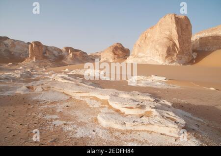 Weiße Kalkfelsen und Inselberge gemischt mit Sand im White Desert National Park, in der Farfara Depression, Sahara-Region, von Ägypten. Stockfoto