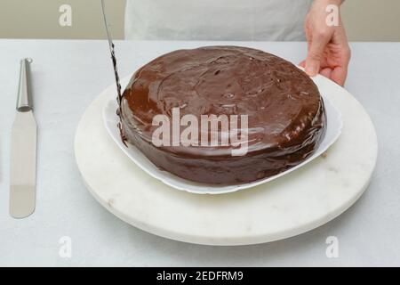 Topping Schokoladenkuchen mit Schokolade Ganache. Schokoladenkuchen mit Schokoladencreme und Schokoladenganache aus nächster Nähe auf dem Drahtgitter auf dem Küchentisch. Schritt Stockfoto