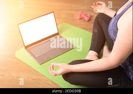 Sukhasana Haltung. Online Yoga Fitness, Laptop mockup. Frau Yoga zu Hause üben. Online-Video-Training. Vierzig-jährige Frau macht Übungen und Stockfoto