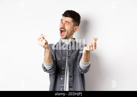 Lustige Kerl zwinkend und zeigt Hand Herzen Zeichen, Gefühl romantisch und glücklich, auf weißem Hintergrund stehen Stockfoto