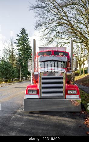 Beliebte leistungsstarke Haube rot klassischen amerikanischen Idol großen Rig semi LKW mit glänzenden Chromteilen und weiß bedecktem Trockenvan Sattelauflieger auf der Stadt geparkt Stockfoto