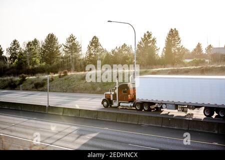 Leistungsstarke Big Rig industriellen klassischen braunen Sattelschlepper Transport Gefrorene gewerbliche Ladung in gekühlten Sattelaufliegern, die zur Auslieferung laufen Ein Stockfoto