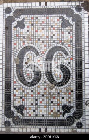 Die Zahl sechsundsechzig, oder neunundneunzig, wenn gedreht. Viktorianisches Mosaik auf dem Bürgersteig vor einem Geschäft im Zentrum von London. Stockfoto