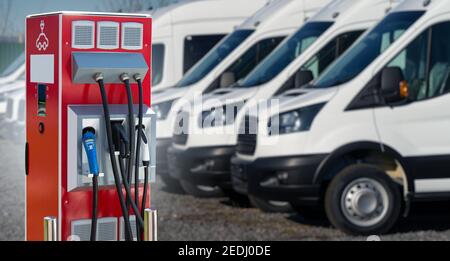 Ladestation für Elektrofahrzeuge auf dem Hintergrund einer Reihe von Transportern. Konzept Stockfoto