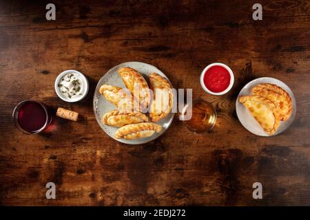 Empanadas, von oben mit Wein und Saucen geschossen, mit einem Platz für Text, auf einem dunklen rustikalen Holzhintergrund Stockfoto